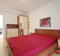 Hálószoba fa mintás padlóval, ággyal, szekrénnyel és képpel egy háromszobás lakásban.