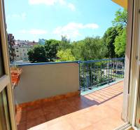 Erkély egy 3 szobás lakásban kilátással a zöld területre és további épületekre.