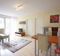 Nappali egy háromszobás lakásban, fa dekoros padlóval, kanapéval és étkezőasztallal.