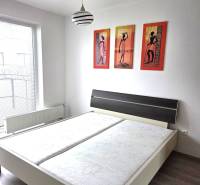 Hálószoba franciaággyal, lámpával és képekkel egy egyszobás lakásban.