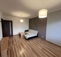 Nappali egy kétszobás lakásban fa dekor padlóval, kanapéval és lámpával.