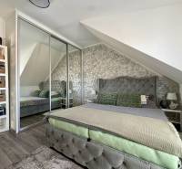 2 szobás lakás belső tere fa mintázatú padlóval, ferde mennyezettel és tükrös szekrénnyel.