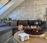 Nappali egy kétszobás lakásban, díszpárnákkal a kanapén és gyertyákkal az asztalon.