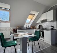 Konyha egy kétszobás lakásban fa dekorációjú padlóval és asztallal székekkel.