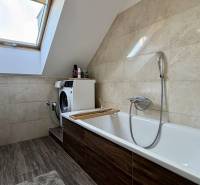 Fürdőszoba tetőablakkal, mosógéppel és fa dekorációjú padlóval egy kétszobás lakásban.