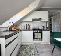 Konyha egy két szobás lakásban ferde mennyezettel és fa dekoros padlóval.