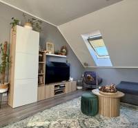 Nappali egy kétszobás lakásban tetőablakkal, fa dekor padlóval, kényelmes bútorokkal.