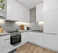 Konyha egy háromszobás lakásban fehér szekrényekkel és fa dekorációjú padlóval.