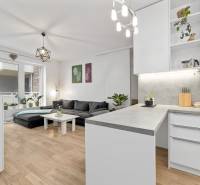 Nappali konyhával egy háromszobás lakásban, fa dekorációjú padló, nagy kanapé.