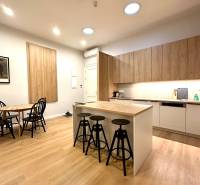 Konyha egy kétszobás lakásban szigettel, székekkel és fa dekorációjú padlóval.