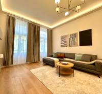 Nappali egy kétszobás lakásban, fa mintázatú padlóval, szürke kanapéval és dekoratív képekkel.