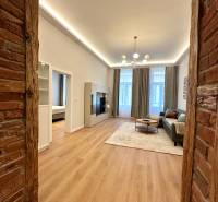 Nappali egy kétszobás lakásban, fa mintázatú padlóval és téglafallal.