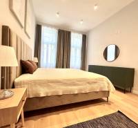 Hálószoba egy kétszobás lakásban nagy ággyal, lámpával és fa dekorációjú padlóval.