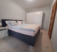 Hálószoba egy háromszobás lakásban ággyal, éjjeliszekrénnyel és szekrénnyel, fa dekorációjú padlóval.