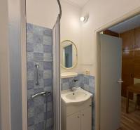 Fürdőszoba egy háromszobás lakásban kék csempékkel és zuhanyzóval.