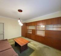 Nappali egy háromszobás lakásban fa faliszekrénnyel és kanapéval.