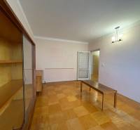 Nappali egy háromszobás lakásban, fa hatású padlóval és bútorokkal.