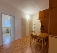 3 szobás lakás belső tere fa mintázatú padlóval, étkező sarok asztallal és székekkel.