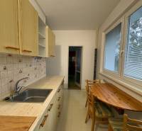 Konyha egy háromszobás lakásban fa dekorációval, faasztallal és csempézett burkolattal.