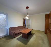 Nappali egy háromszobás lakásban kanapéval, dohányzóasztallal és vitrinnel.