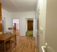 3 szobás lakás belső tere fa dekorációjú padlóval, asztallal és székekkel.