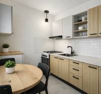 Konyha egy háromszobás lakásban fa dekorációval, fehér csempékkel és kerek asztallal.