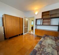 Egy háromszobás lakás szobája fa bútorokkal és fa dekorációjú padlóval.