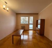 Nappali egy háromszobás lakásban, fa dekoros padlóval és egyszerű bútorokkal.