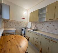 Konyha egy háromszobás lakásban, asztallal, csempével és hangulatos főzőtérrel.