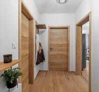 Folyosó egy kétszobás lakásban fa ajtókkal és fa dekorációjú padlóval.