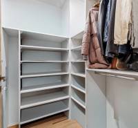 Gardrób polcokkal és akasztókkal egy kétszobás lakásban, fa dekor padlóval.