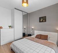 Hálószoba egy kétszobás lakásban fa mintázatú padlóval és modern bútorokkal.