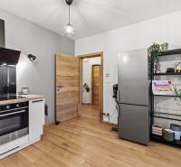 A kétszobás lakás konyhája fa mintázatú padlóval, hűtőszekrénnyel és polcos állványokkal.