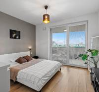 Hálószoba egy kétszobás lakásban ággyal, fa dekoros padlóval, erkélyajtóval.