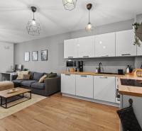 Nappali konyhával egy kétszobás lakásban, fa hatású padlóval és kanapéval rendelkezik.