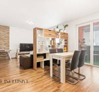 Nappali étkezőasztallal egy kétszobás lakásban, fa mintázatú padló, könyvtár.