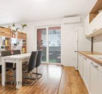 Konyha egy 2 szobás lakásban étkezőasztallal és fa dekorációjú padlóval.