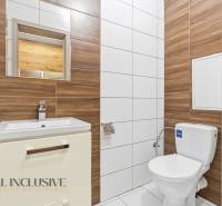 Fürdőszoba kétszobás lakásban WC-vel, mosdóval és fa dekoros csempékkel.