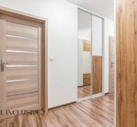 Folyosó egy kétszobás lakásban fa dekoros padlóval és tükrös szekrénnyel.