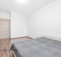 Hálószoba egy kétszobás lakásban fa mintázatú padlóval és tágas szekrénnyel.