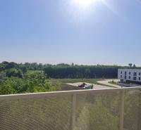 Kilátás az erkélyről Pozsonyban - Ružinovban az Ivanská úton épületekkel és zölddel.