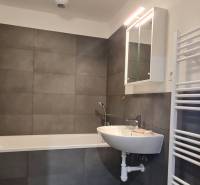 Fürdőszoba egy kétszobás lakásban káddal, mosdóval és tükrös szekrénnyel.