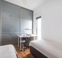 Hálószoba a nyaraló apartmanban tolóajtós szekrénnyel és ággyal, fa dekorációs padlóval.