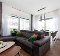 Nappali a nyaraló apartmanban kanapéval, fa hatású padlóval és étkezőasztallal.