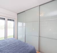 Hálószoba egy üdülőapartmanban nagy beépített szekrénnyel és ággyal kék takaróval.