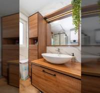 Fürdőszoba egy nyaraló apartmanban mosdóval, fa bútorokkal és fa dekorációjú padlóval.