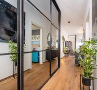 Nyaraló apartman belső tere fa dekor padlóval, tükrös fallal és növényekkel.