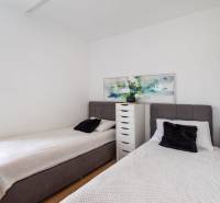 Két egyszemélyes ágy és egy komód a nyaraló apartmanban, fa dekor padlóval.