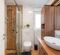 Fürdőszoba egy üdülő apartmanban, fa dekorációjú padlóval és modern felszereléssel.