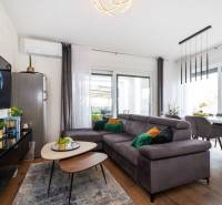 Nappali a nyaraló apartmanban kényelmes kanapéval és fa dekorációjú padlóval.